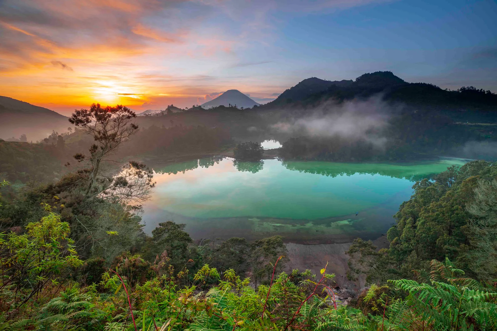 Panorama Telaga Warna dengan danau hijau dan pegunungan Dieng
